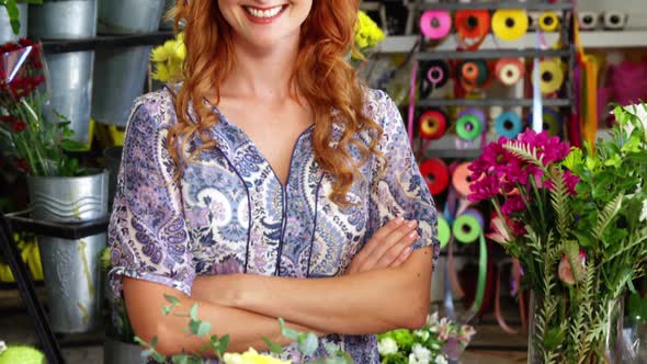 Happy female florist standing with arms crossed in flower shop alt