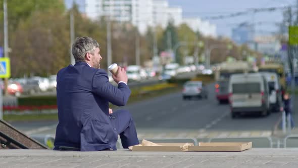 Businessman having snack outside in the centre of the city