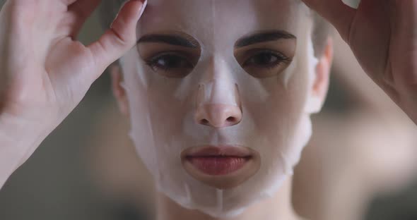 Portrait of a Beautiful Woman, Paper Sheet Masks on Face, Female Slowly Removes a Beauty Mask From alt