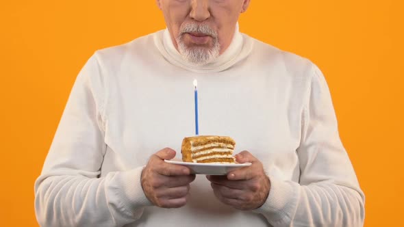 Sad Retired Man Blowing Cake Candle Feeling Lonely on Birthday, Disappointment alt