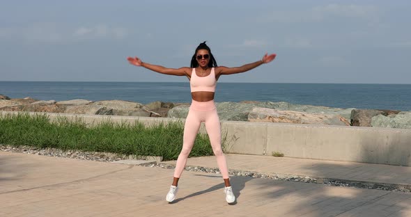 Young fit sporty black African woman does leaning forward exercise working out outdoor on summer.