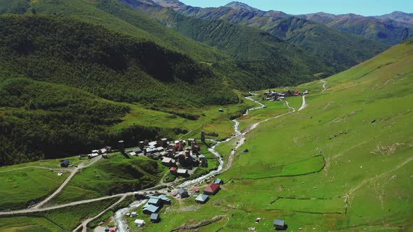 Aerial View of a Mountain Village Along the River in the Middle of a Sunny Summer Day alt