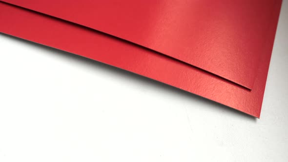 4k video, close-up of red paper sheets, laid out on a white background, top view.