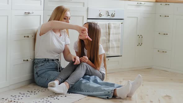 Mature Loving Emotional Mother with Long Hair Sits on Kitchen Floor with Teenage Daughter and Girl alt