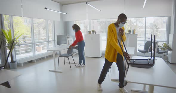 African Colleagues in Protective Mask Arranging Furniture in Empty Office