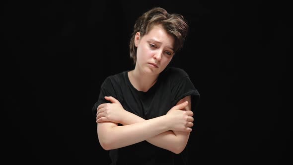Slim Beautiful Depressed Woman with Crossed Hands Posing at Black Background alt