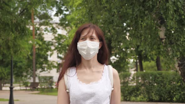 Protective Mask on Face of a Young Girl Outdoors in Park. Girl on City Street Travels in Medical alt