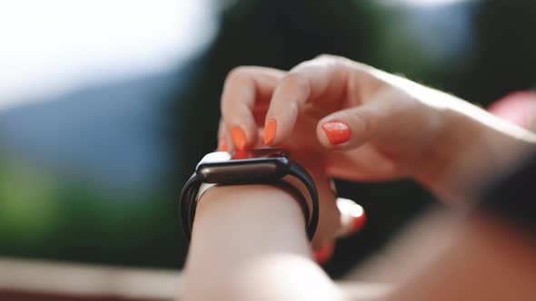 Young Woman Using Smart Watch Outdoor Touch Screen on Watch Entering Watch App Scrolling on Display