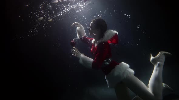 Slim Woman Dressed Santa Suit Is Floating Underwater Mascarade and Costume Party in Pool alt