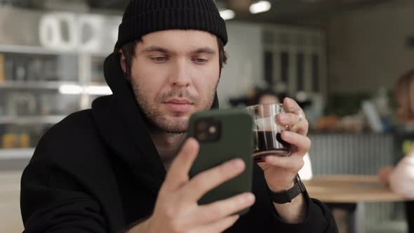 Relaxed Guy Sitting at Cafe Table with Mobile and Coffee alt