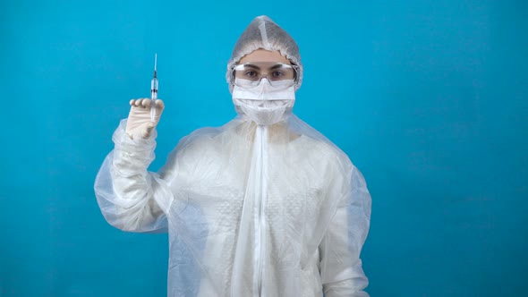 Young Woman in a Protective Suit with a Syringe in His Hand. A Girl Holds a Vaccine Against the alt