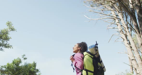 Smiling biracial woman looking away and hiking in countryside alt