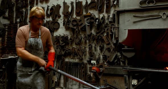 Blacksmith hammering a hot metal rod  alt