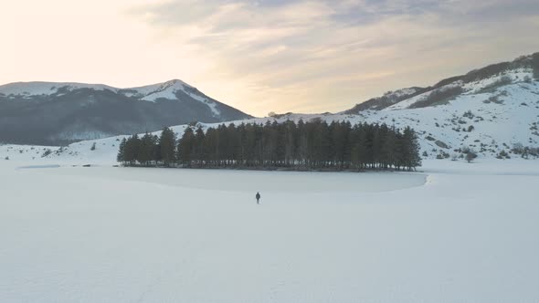 Young man walking on mountain at sunset, drone shot winter