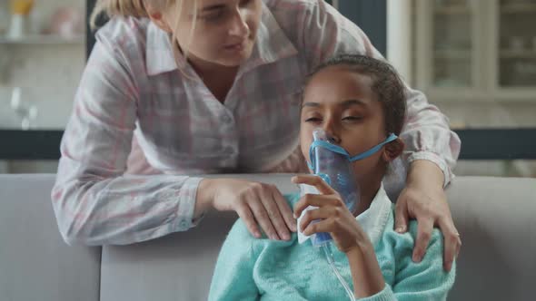 Caring Mom Supports Unwell Child in Nebulizer Mask alt