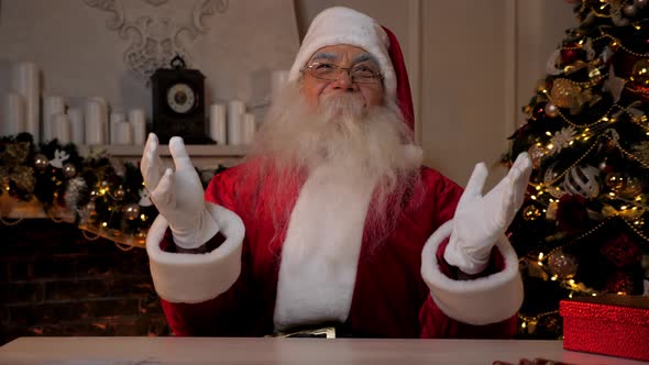 Laughing Santa Claus Looks Camera Sitting on Chair at Desk alt