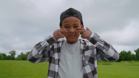 Boy Baseball Player Applying Eye Black Underneath Eyes Outdoors alt