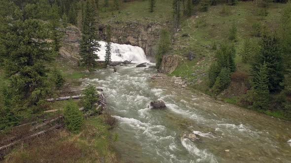 Flying over river towards waterfall in the Wyoming mountains alt