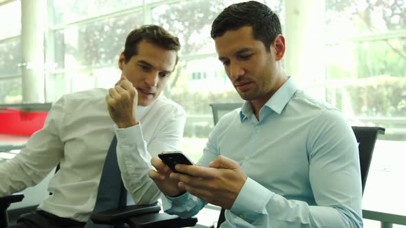Businessman assists colleague with using smartphone