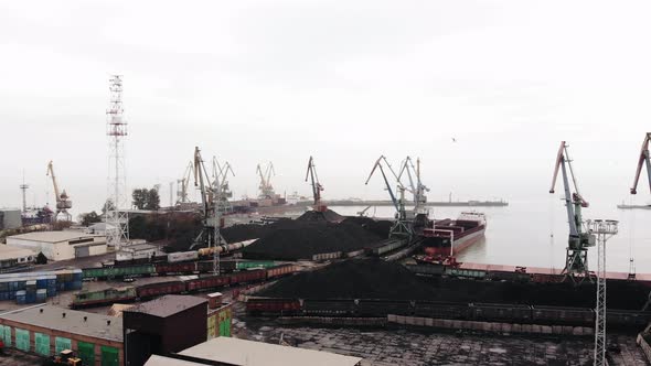 Shooting From Drone of a Sea Cargo Port with Tower Cranes and Tankers and Ships Sailing Across the