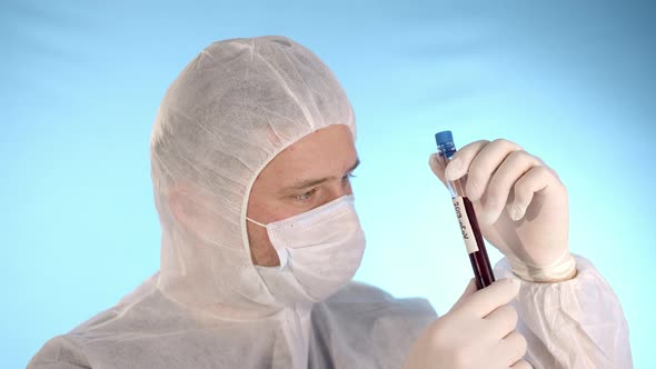 Man in Protective Suit Medical Mask Gloves Holds Test Tube with Coronovirus
