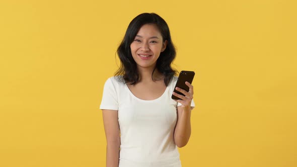 Causal beautiful Asian woman reading message in smart phone and smiling