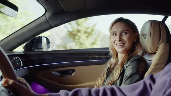 The passenger girl talks to the driver, pats his hand.