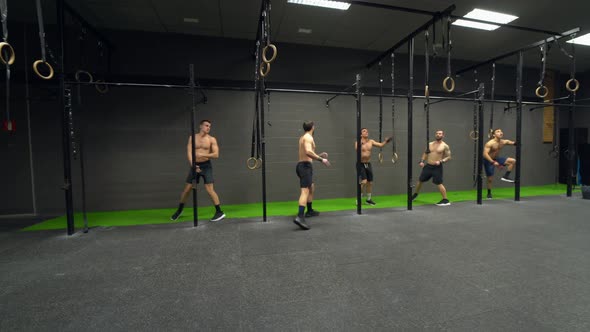 Group of athletes exercising swing ups on rod at gym
