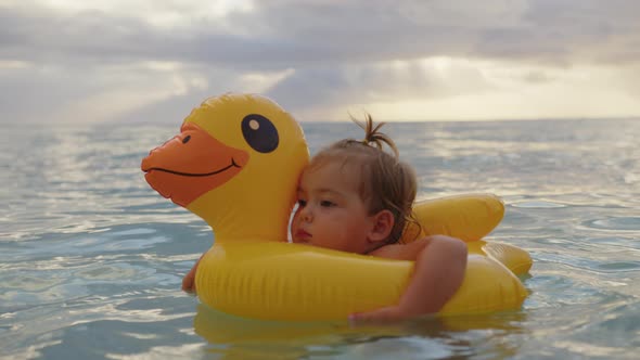 Adorable Baby Girl Swimming with Inflatable Duck in Indian Ocean alt