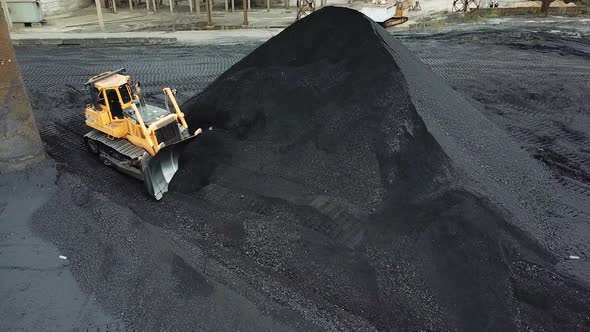 Yellow bulldozer moves the coal. Extractive industry. Aerial view. alt