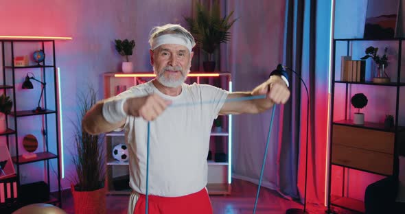 Old Bearded Man in Sportswear Doing Strength Exercises Using Resistance Rubber Band alt