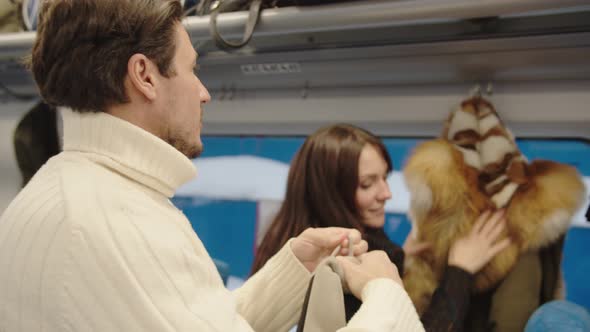 A Middleaged Couple Hangs Their Outerwear in Their Seats in a Train Carriage