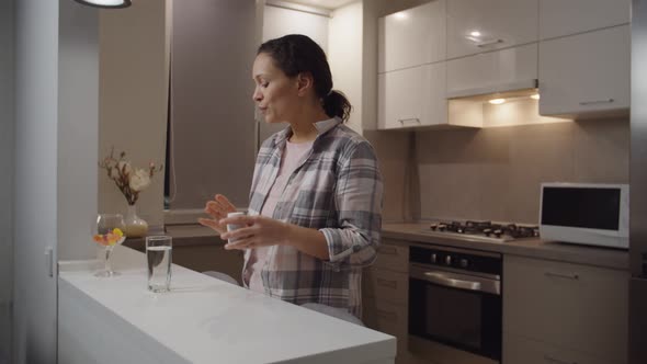 Adult Woman Taking Daily Medication or Vitamin Supplements at Home alt