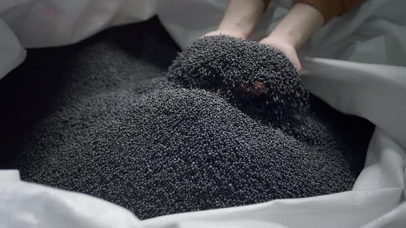 Hands Lift Polymer Granules From a Bag in a Garbage Recycling Plant alt