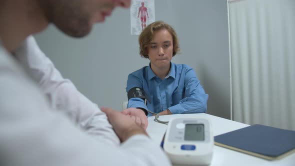 Boy Sit in Cabinet of Hospital, Doctor Take His Blood Pressure 