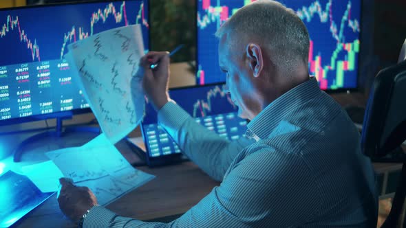 A Trader is Looking at the Reports with Stock Market Information alt