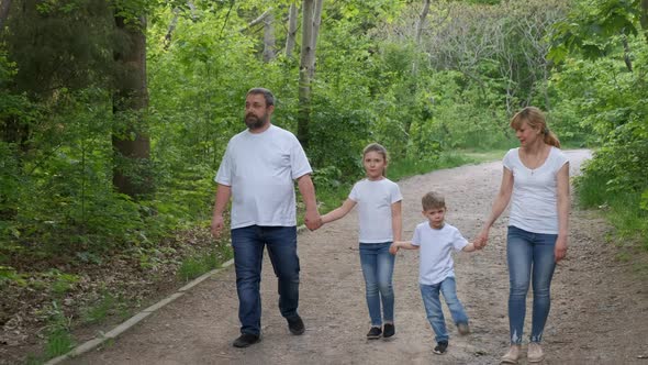 Family: father, mother, son and  daughter  walk in the Park in  white t-shirts 