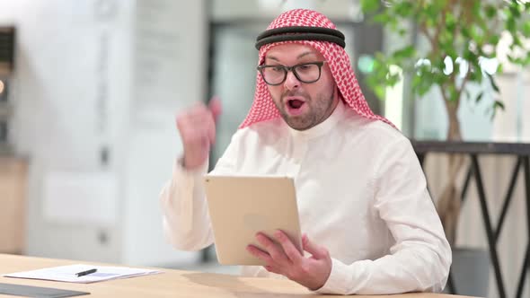 Successful Young Arab Businessman Celebrating on Tablet in Office alt