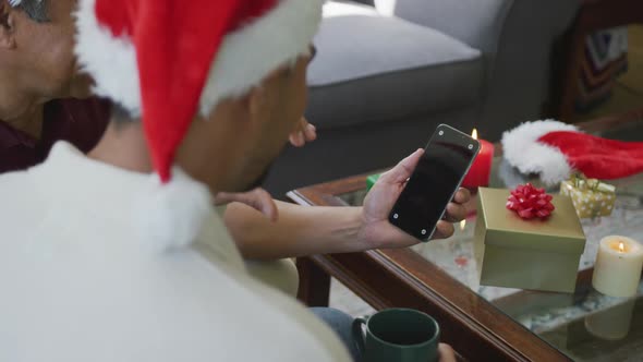 Son and father making christmas video call on smartphone with blank screen and copy space at home alt