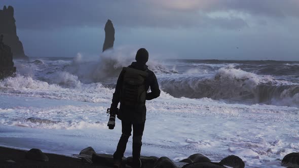Photographer On Black Sand Beach Watching Stormy Sea alt