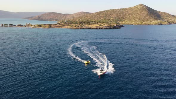 Aerial View of a Motor Boat Towing a Tube. Elounda, Crete, Greece