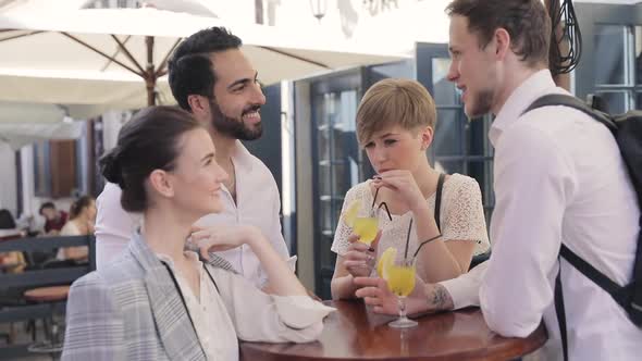 Young People Drinking Cocktails At City Street Cafe alt