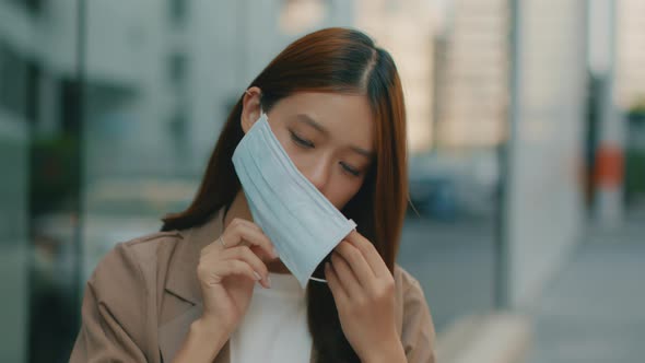 Asian Businesswoman wearing medical face mask standing on the street and looking at camera