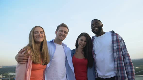 Company of Multiracial Friends Laughing at Camera, Relaxing Together Outdoors