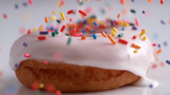 Sprinkling candy chocolate on frosted doughnut. Slow Motion. alt