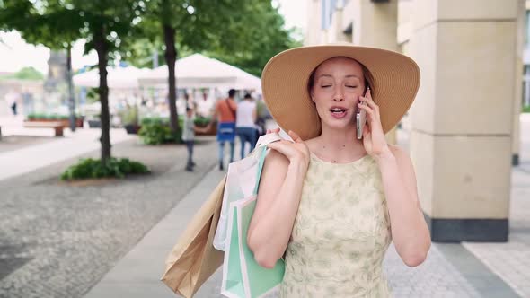 Young Fashion Woman Talking on Phone Holding Shopping Bags Walking on Street