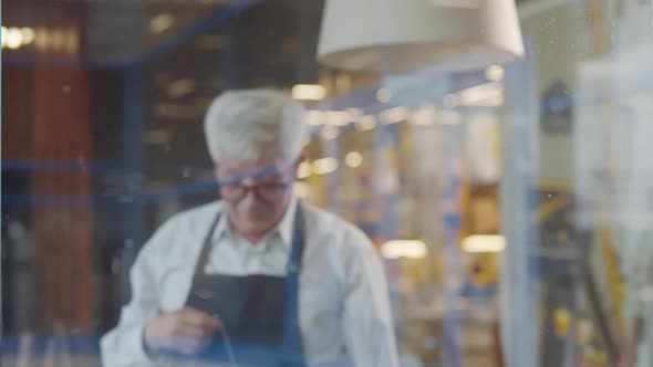 Mature Owner Hang Takeaway Only Sign on Cafe Glass Door alt
