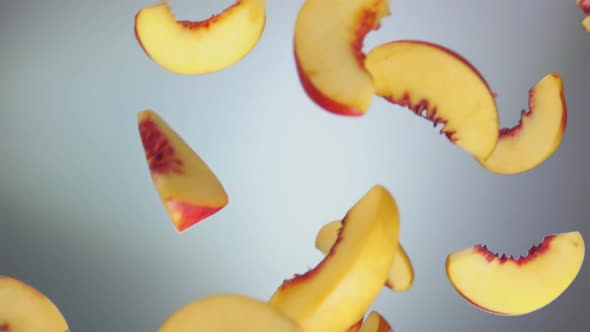 Closeup of the Juicy Peach Slices Falling and Spinning on the White Background alt