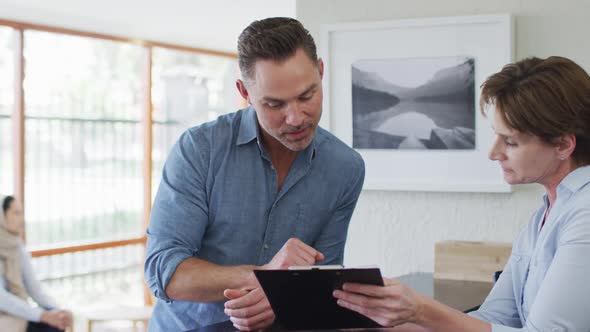 Smiling caucasian man talking and signing documents at reception at modern dental clinic alt