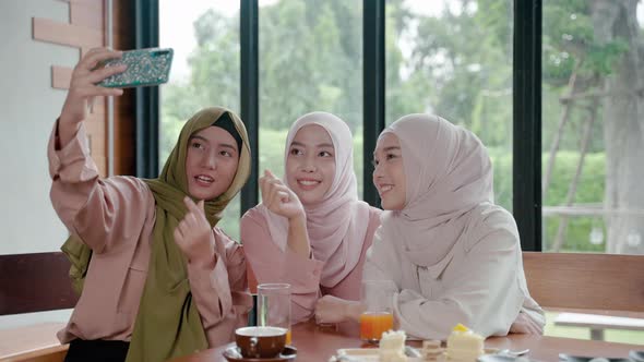 group of Muslim girls dining in a restaurant is using their mobile phones to chat online with their